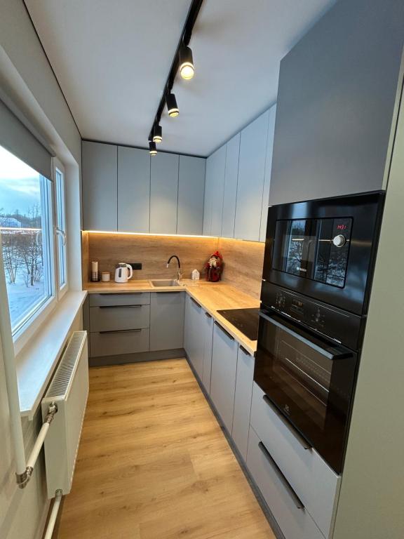 a kitchen with white cabinets and a black microwave at Апартаменты Toome в Кохтла-Ярве in Ahtme