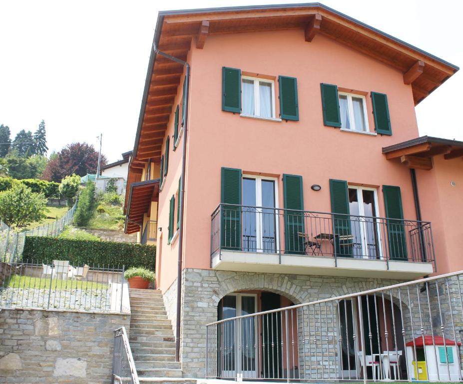 ein rosafarbenes Haus mit grünen Rollläden und Treppen in der Unterkunft Casa la Pianca in Menaggio