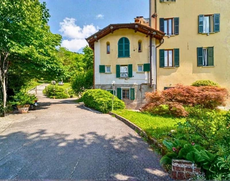 a large house with a driveway in front of it at Tiny Apartment on the Lake in Tremezzo