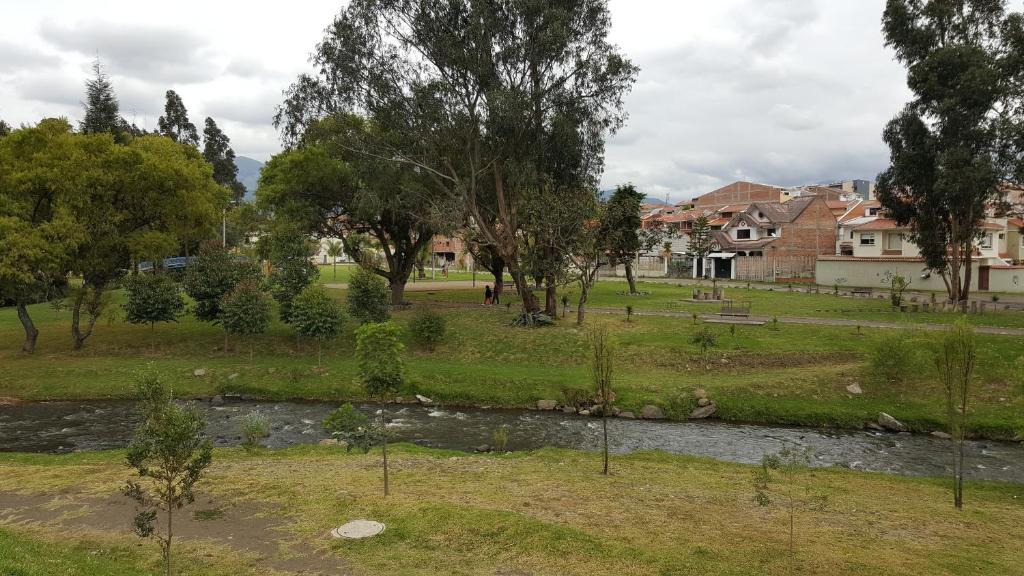 a park with a river and trees and houses at Casa Vacacional in Cuenca