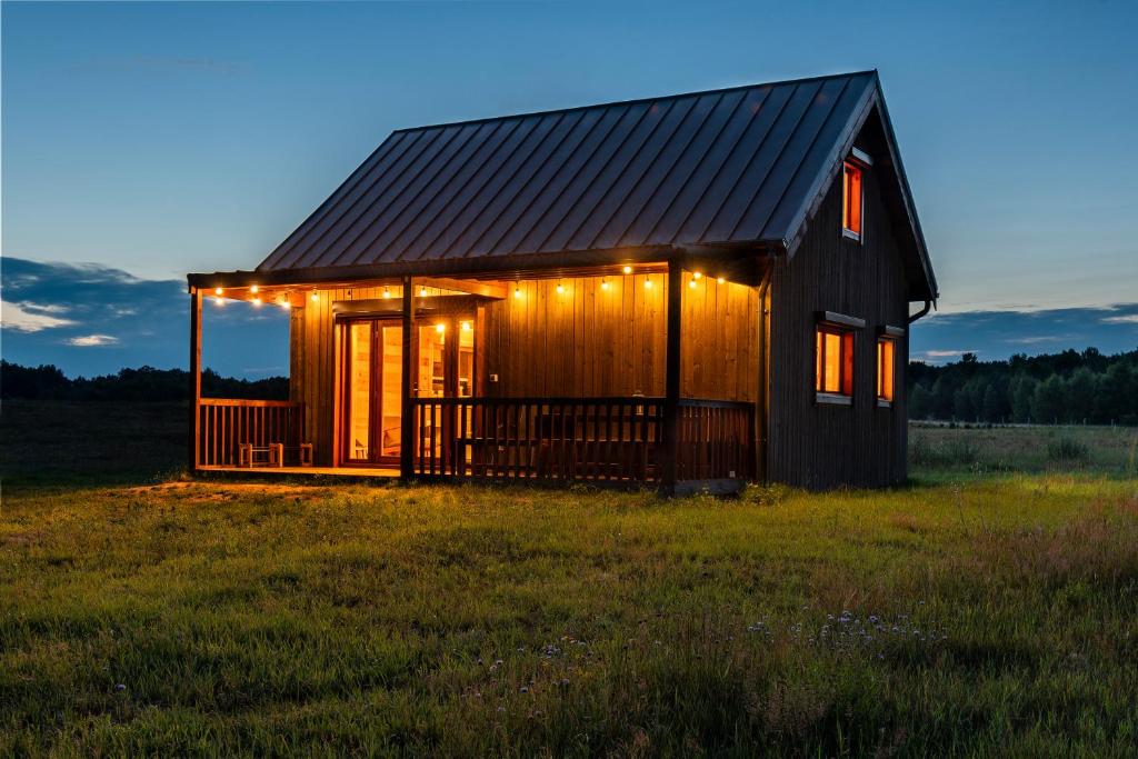 a small house with lights on it in a field at Dom nad Ińskiem in Scienne