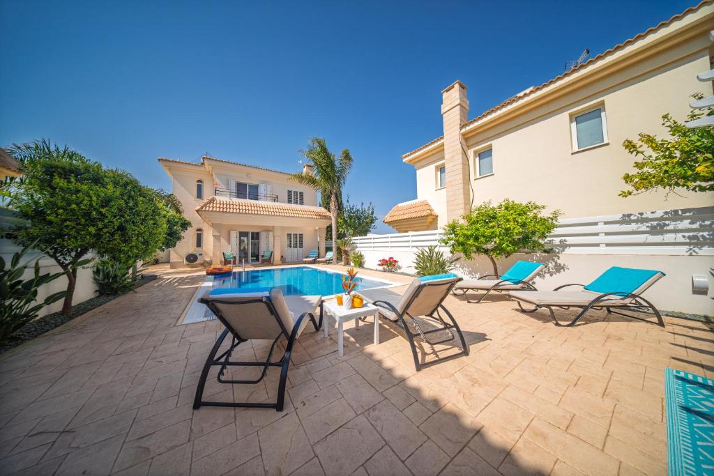 a patio with chairs and a table next to a house at Palm Villa Eva in Paralimni