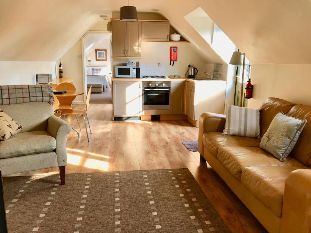 a living room with a couch and a kitchen at The Hayloft, Wonderful Riverside Accommodation in Bodenham