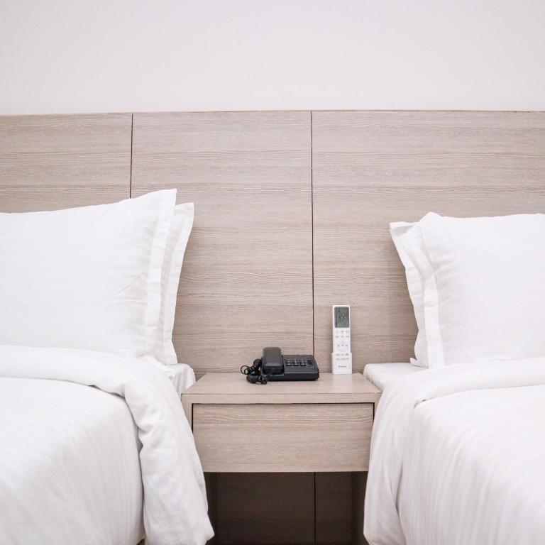 a hotel room with two beds and a phone on a night stand at Hotel Kantipur Plaza in Nepālganj