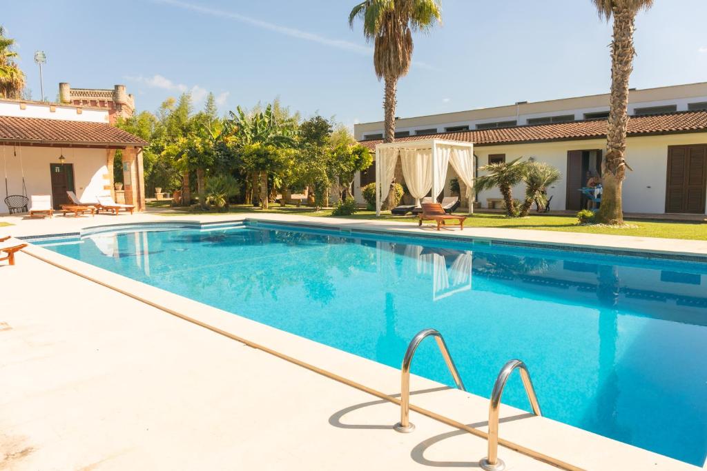 a swimming pool in a resort with palm trees at Villa Padula in Sogliano Cavour