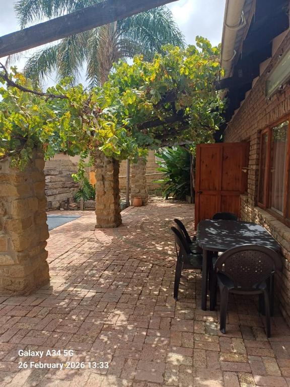 a patio with a table and chairs and trees at 21A On VDR in Oudtshoorn