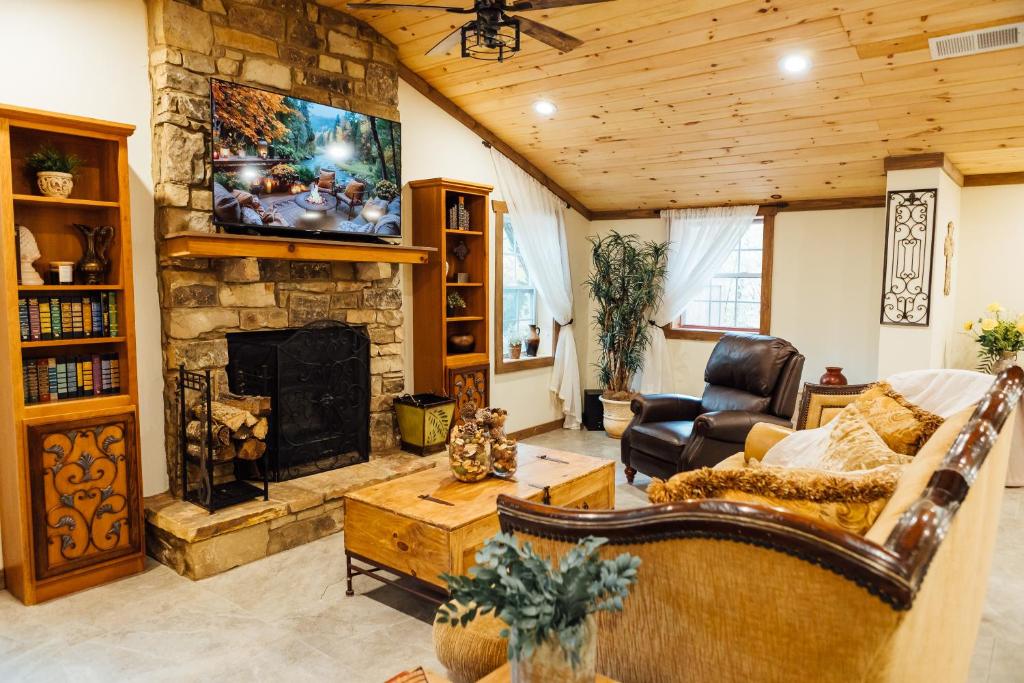 a living room with a stone fireplace and a tv at Villa Serena Tuscan Theme home with a HIDDEN lounge, fire pit, lawn games, creek in Dahlonega