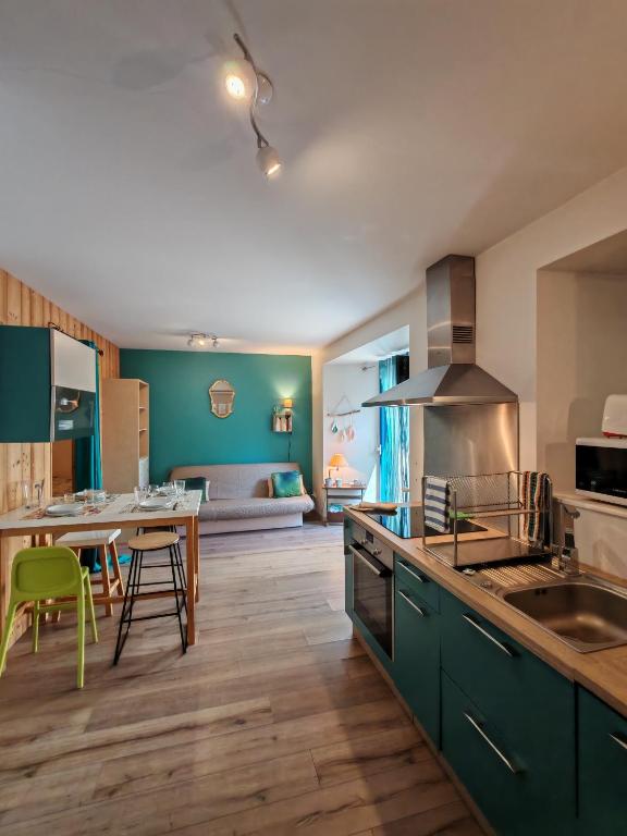 a kitchen with green cabinets and a table with a dining room at Gites du Rioul in Les Estables