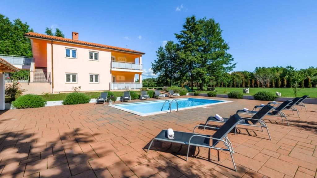 a swimming pool with chairs and a house at Villa Roberta by Villas Guide in Pazin