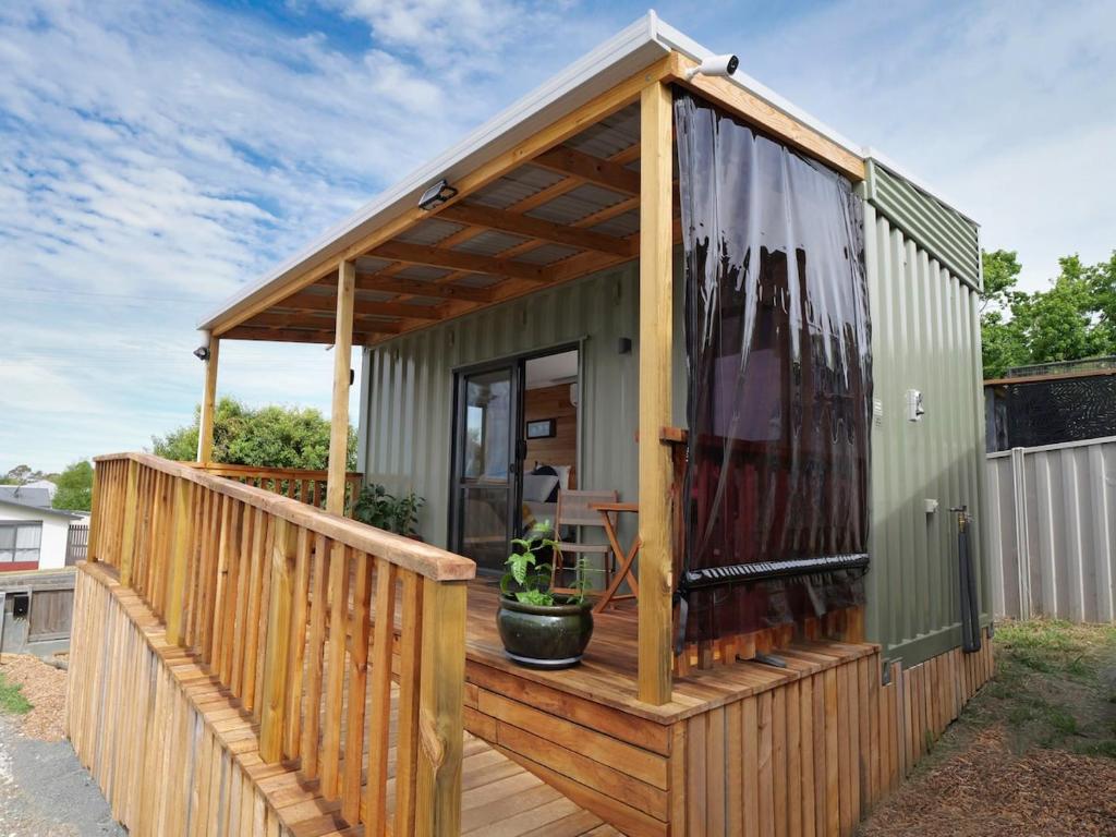 a green tiny house with a wooden deck at Leven Studio - StayTiny at Ulverstone in Ulverstone