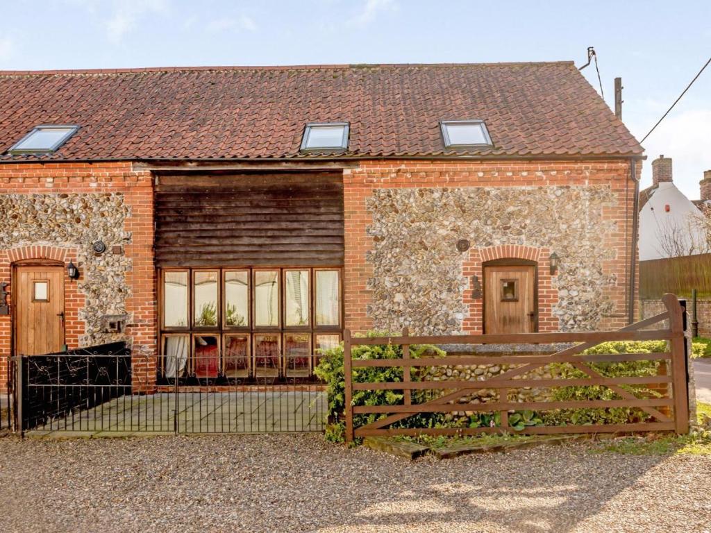 a brick house with a wooden fence in front of it at 3 Bed in Norwich oc-owln8 in Corpusty