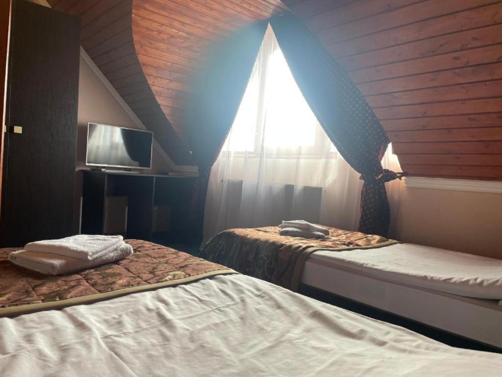 a room with two beds and a window with a roof at Karikás Apartman in Hajdúszoboszló