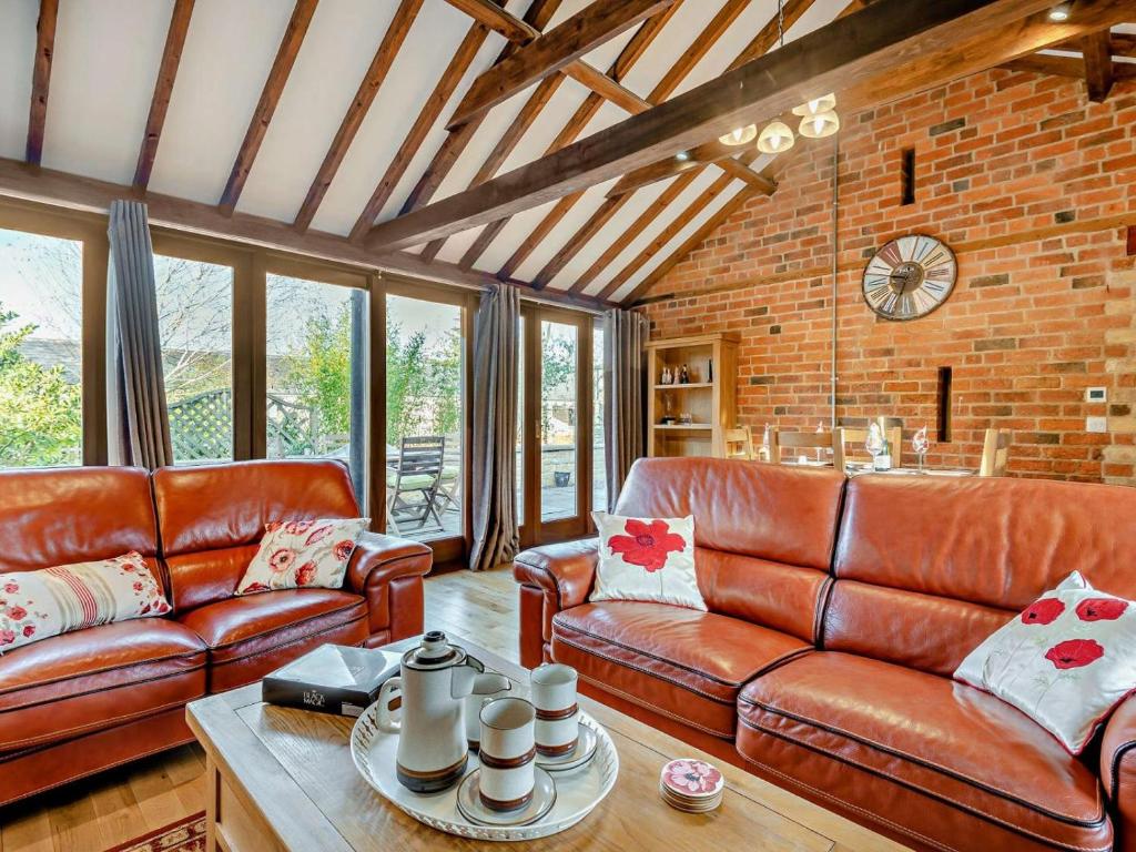 a living room with leather furniture and a brick wall at 2 Bed in Lincoln oc-91059 in Ashby de la Launde