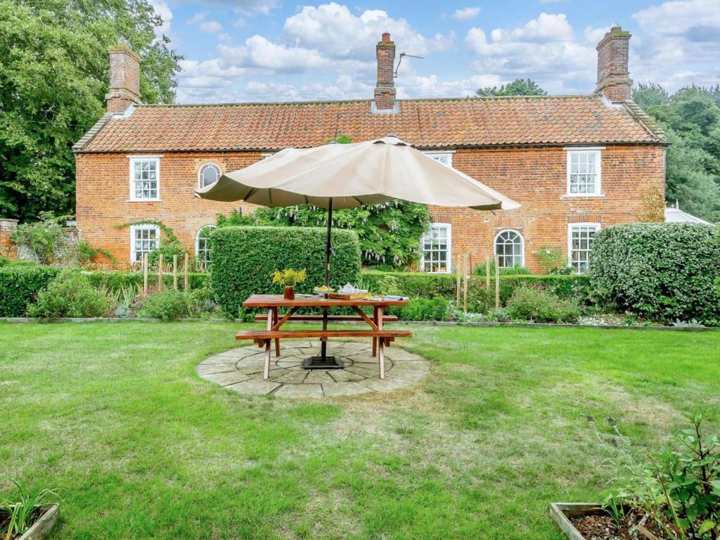 a picnic table with an umbrella in front of a house at 5 Bed in Dereham oc-89542 in Swanton Morley