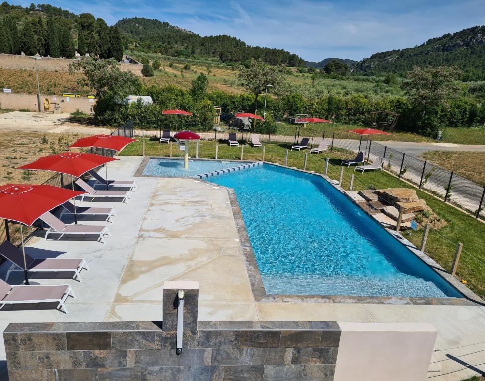 a pool with umbrellas and chairs and a resort at Flower Camping de L Olivigne in Bize-Minervois