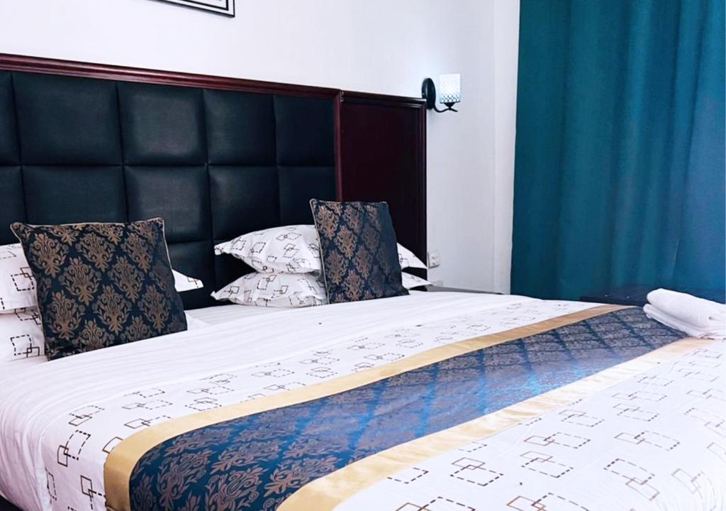 a large bed with a black headboard and pillows at Mika Lodge in Lusaka