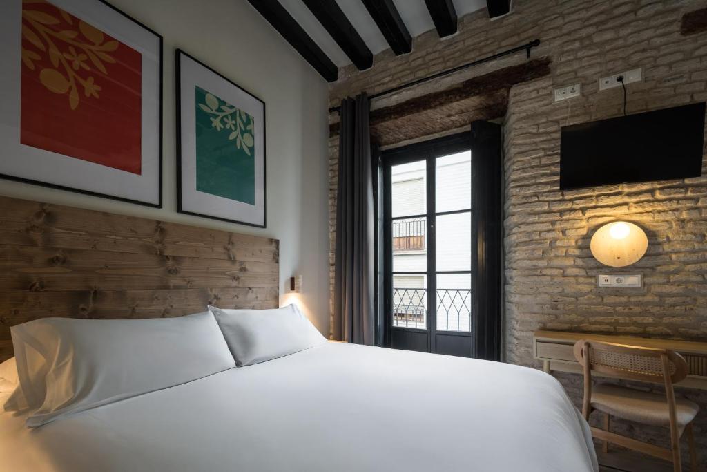 a bedroom with a large white bed and a window at Casa Tomás Boutique Hotel in Seville