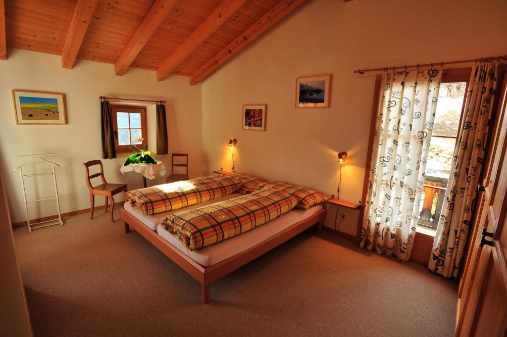 a bedroom with a bed and a chair and a window at Bed & Breakfast La Val in Trin