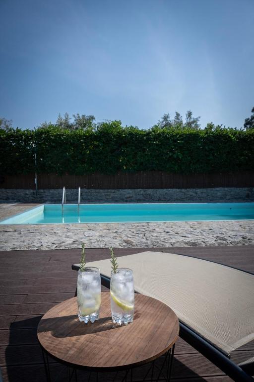 a table with two glasses of water and a pool at WABI SABI-QuintAlão in Passô