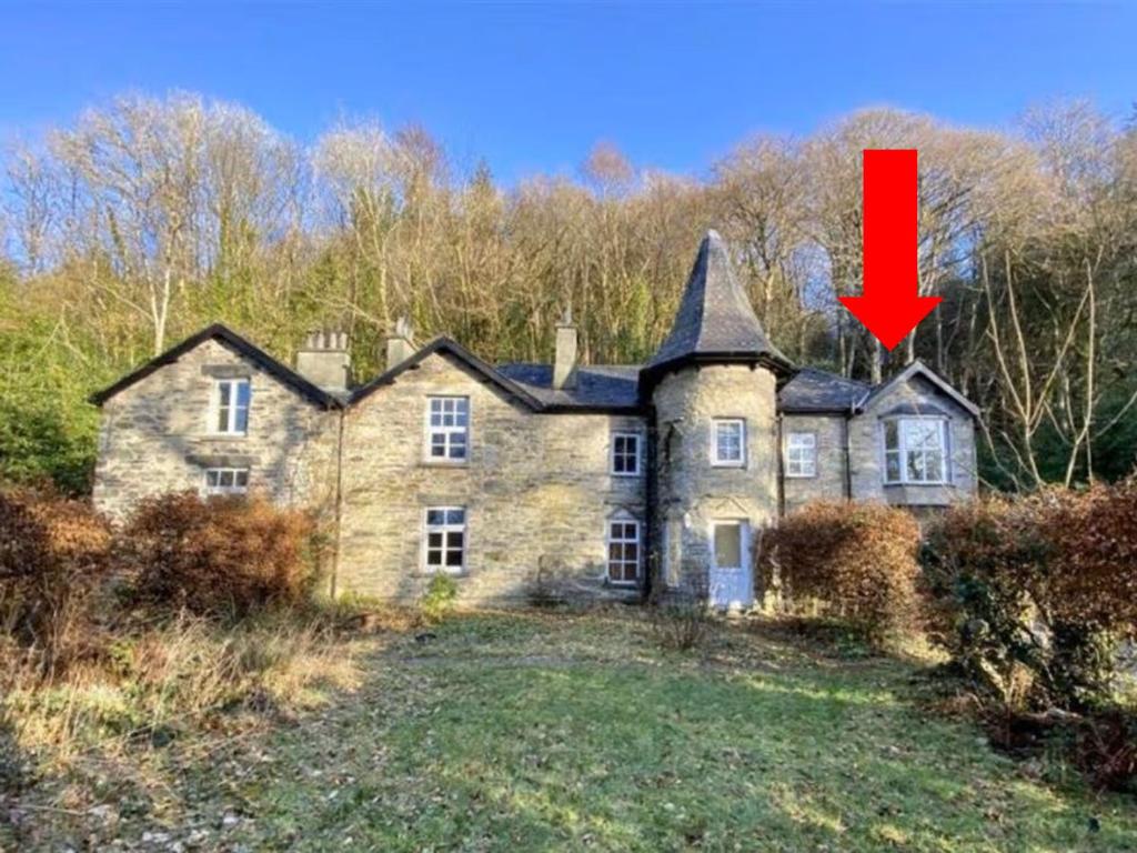 an old stone house with a red arrow on it at 1 Bron Rhedyn Holiday Cottage in Betws-y-coed