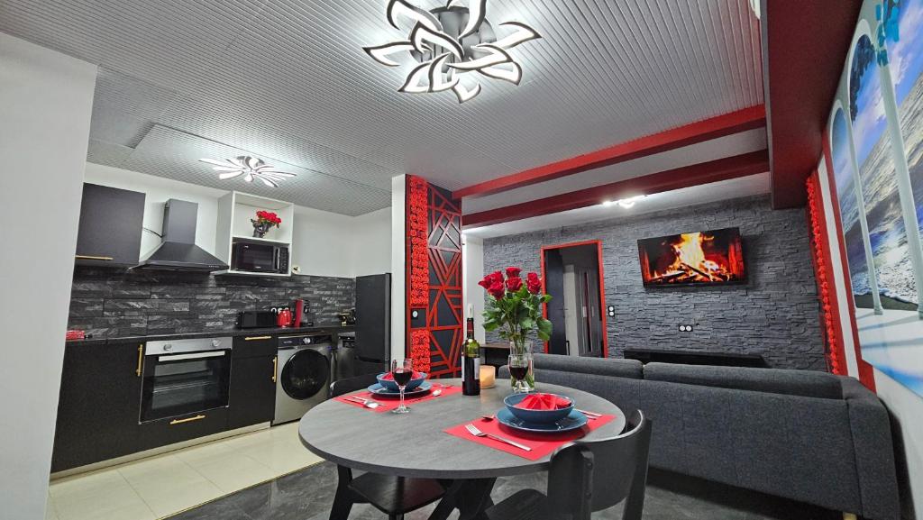 a kitchen and living room with a table and a couch at La Suite Rouge Proche Paris & Stade De France in Drancy