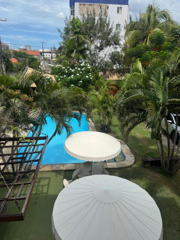 two white umbrellas sitting next to a swimming pool at Casa de Temporada in Caucaia