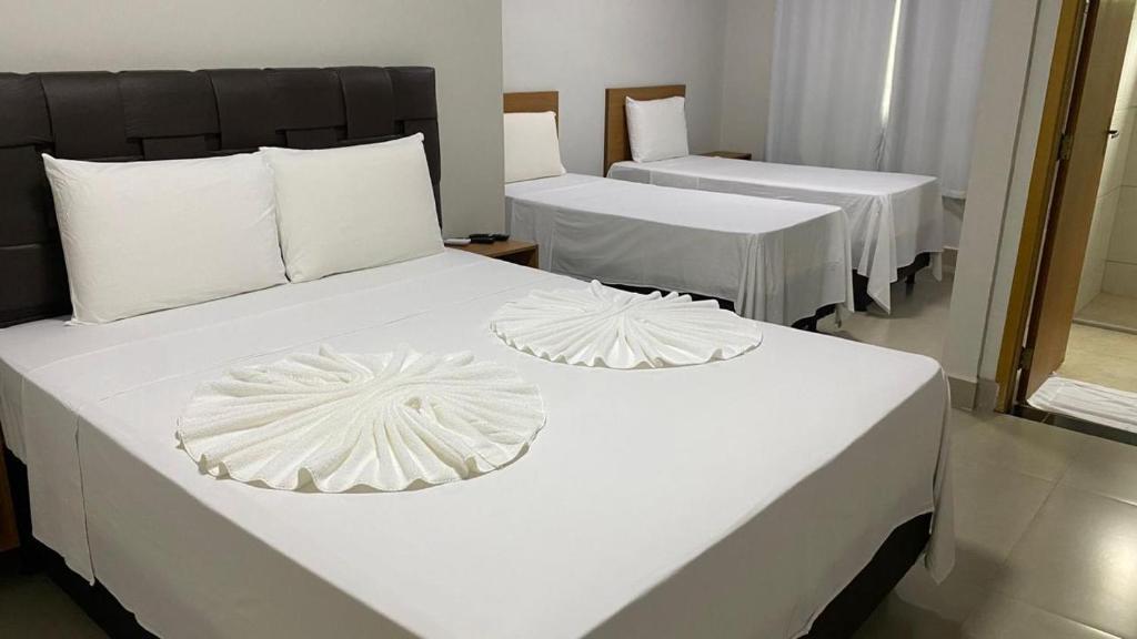 two beds in a room with white sheets and pillows at Executive Hotel Aguas lindas GO in Macacos