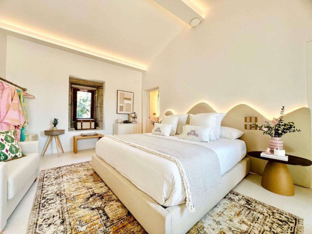 a white bedroom with a large bed and a couch at Aldea Calma in Sanxenxo