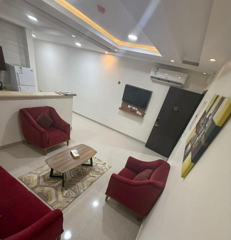 a living room with two red chairs and a table at ثار بارك للشقق المخدومة in Qushayya