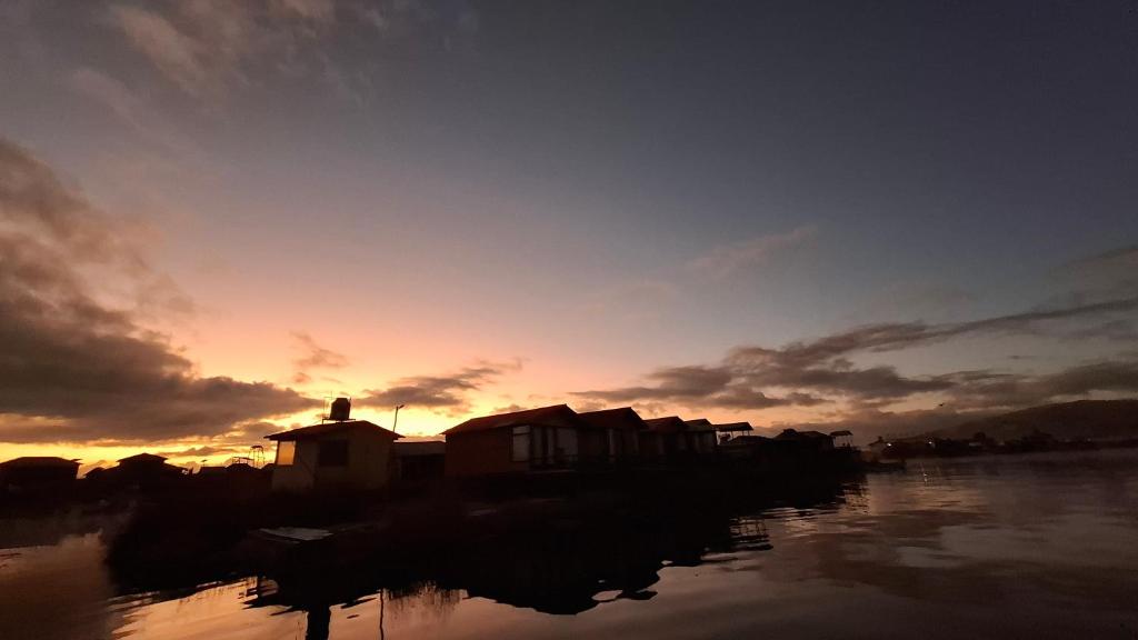 a group of houses on the water at sunset at Uros & Titicaca Sunset Comfort Floating cabins in Puno