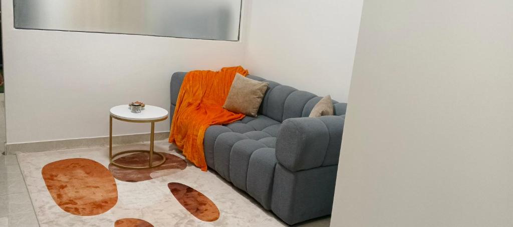 a living room with a blue couch and a table at Fun-fantastic Furnished Apartment, The Loftel near UN, Embassies, Two Rivers & Village Market,with a Pool and Gym in Nairobi