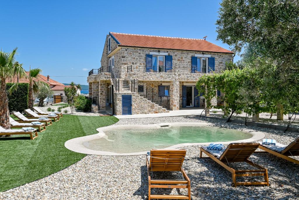 a house with a swimming pool with two lawn chairs at Magna in Dobropoljana