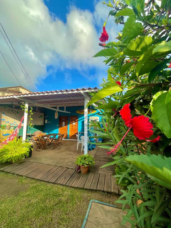 a house with a wooden deck with red flowers at Estação Noronha in Fernando de Noronha
