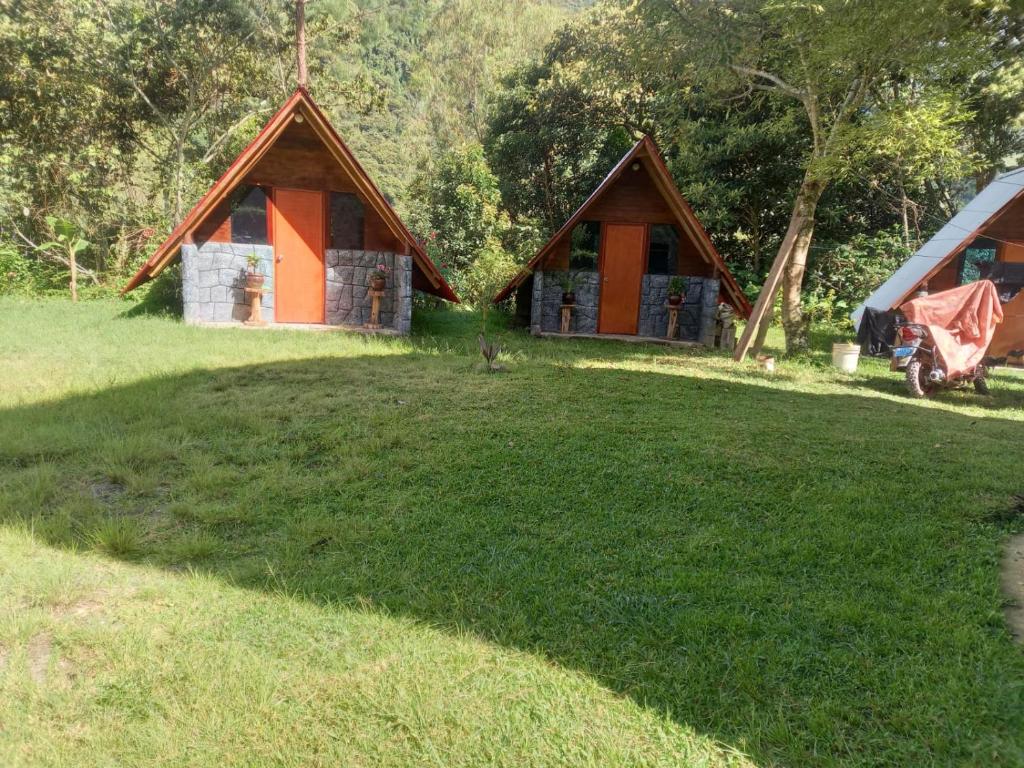 a couple of huts in a field with a grass yard at Lucmabamba Cabaña de los Duendes in Sahuayacu
