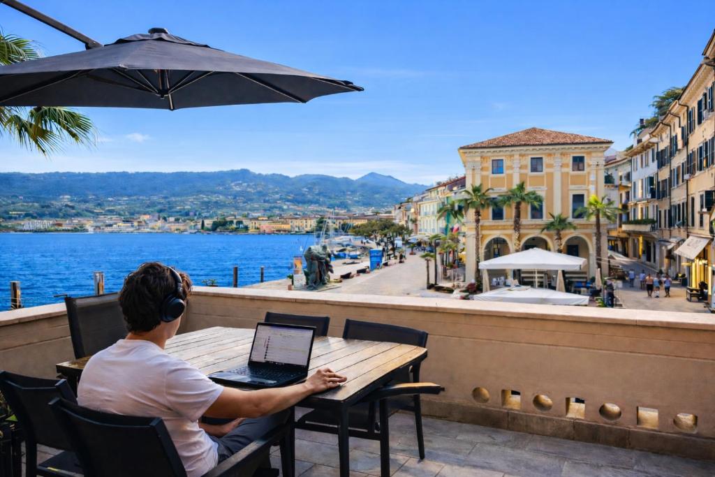 a man sitting at a table with a laptop on a balcony at DIMORE DEL CENTRO - Domus Aurea in Salò