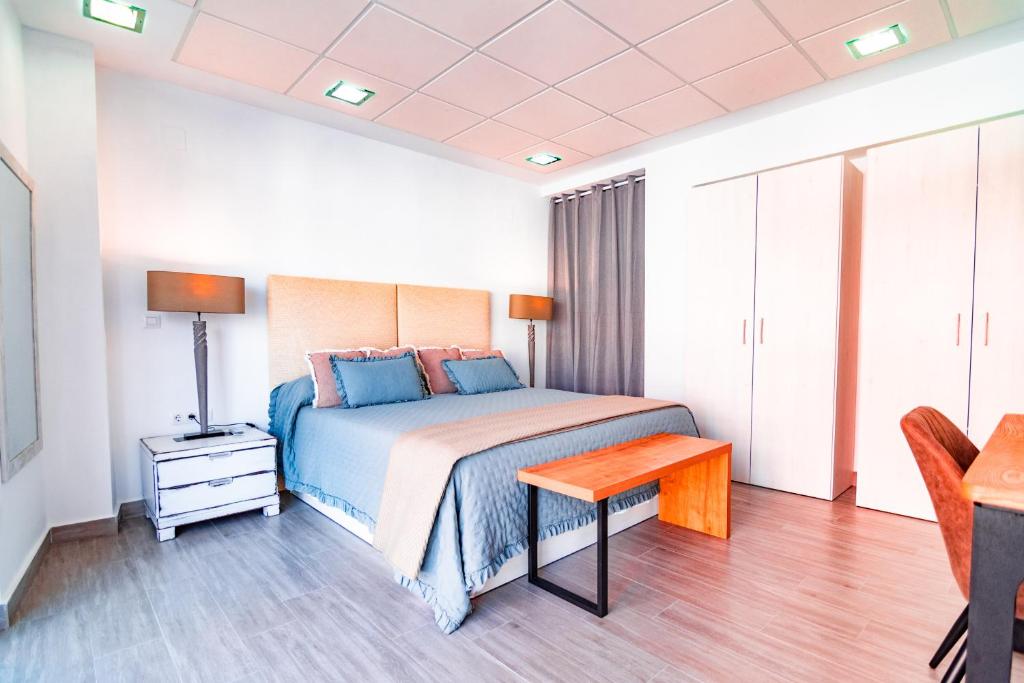 a bedroom with a bed with a table and a lamp at EDomus Medellin 1485 Suites in Don Benito