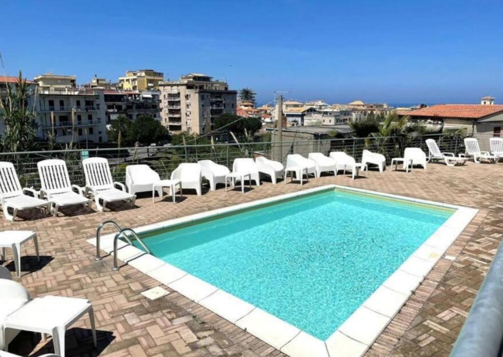 a swimming pool with white chairs and a bunch ofitures at Astrea Apartament in Tropea