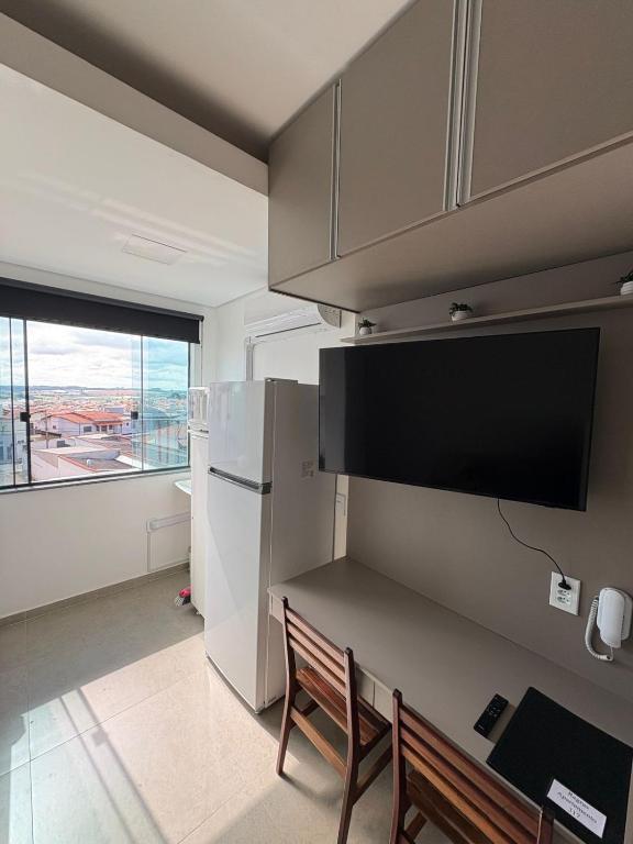 a kitchen with a refrigerator and a table and chairs at Smart Studio Lavras in Lavras