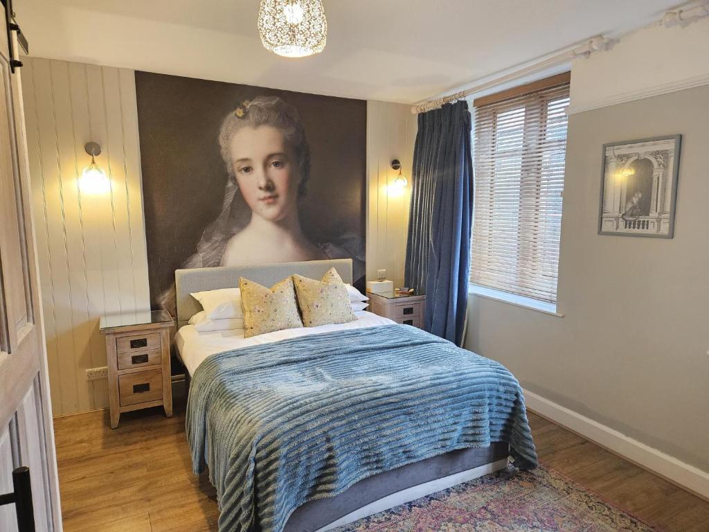 a bedroom with a portrait of a woman on the wall at Cotswold Gardens Bed and Breakfast in Stow on the Wold