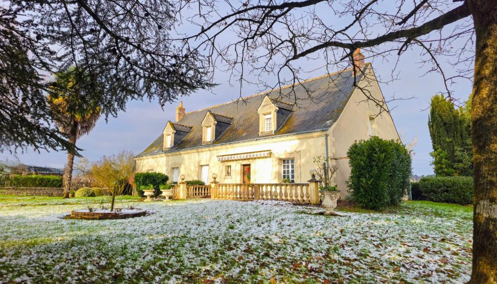 an old house with snow on the ground in front of it at La maison du pont du gué in Bourgueil