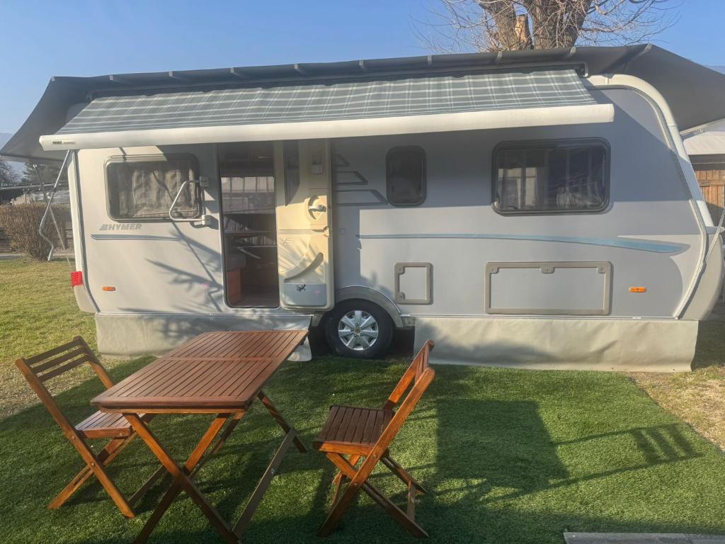 a caravan with a table and two chairs in a yard at Camping Alex in Cadenazzo