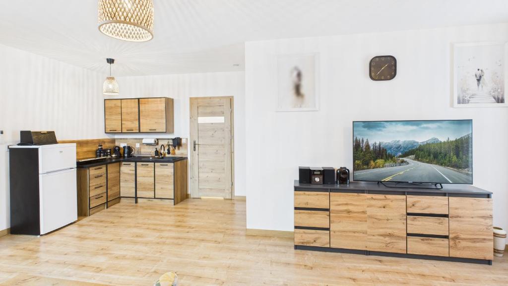 a kitchen with a flat screen tv on the wall at Dębówka - apartament rodzinny in Wilcze