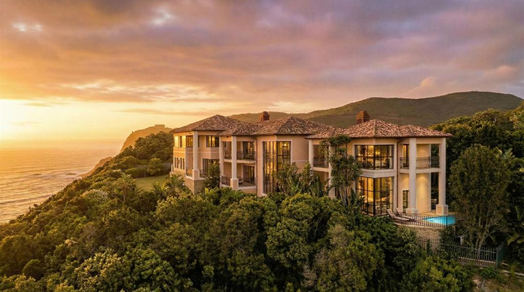 a house on a hill next to the ocean at Villa Seaview, Private Oceanfront Villa, Heated Pool & Whale Watching Views, Knysna Heads in Knysna