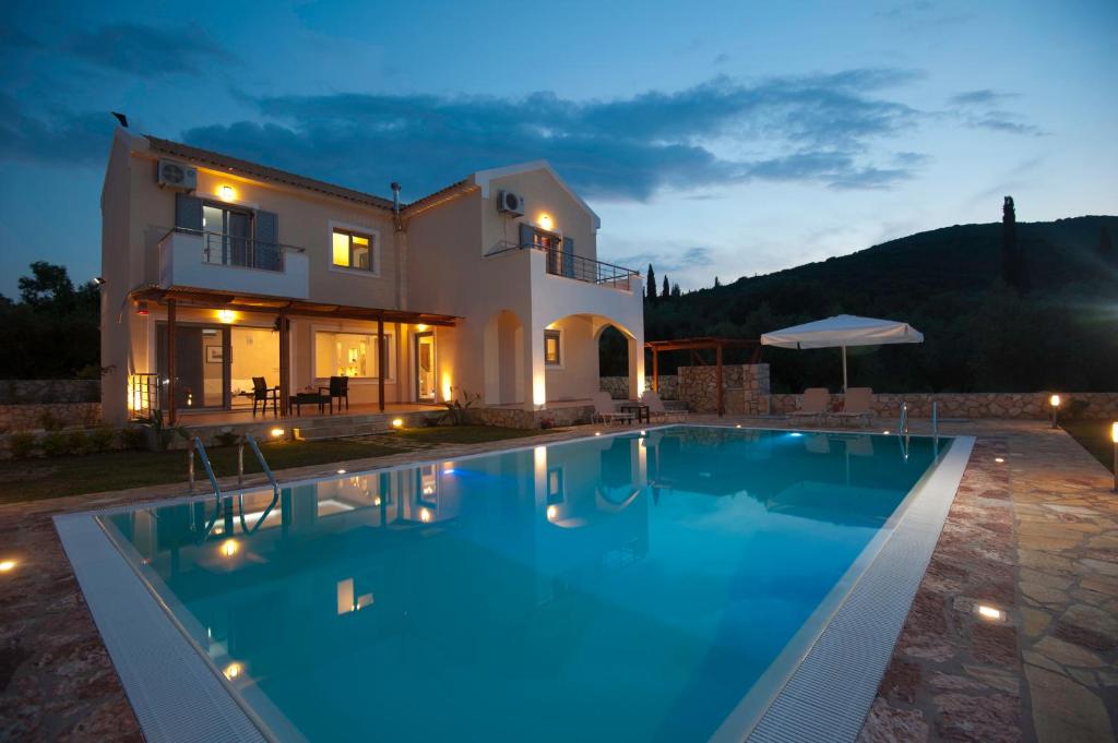 a villa with a swimming pool in front of a house at Villa Harmony in Karavomylos