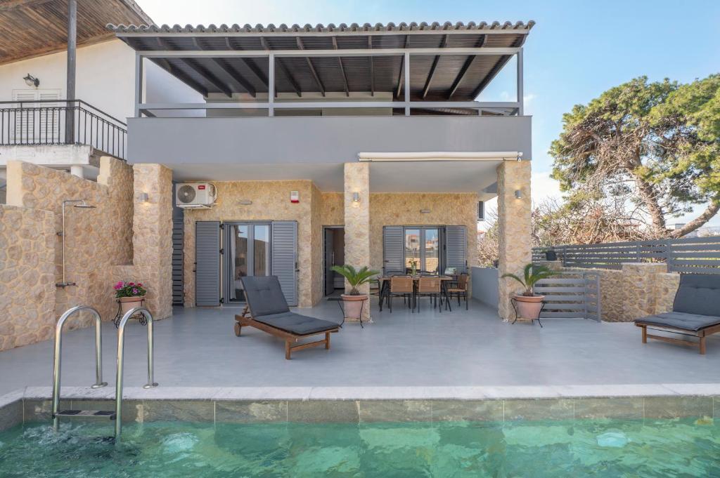 an outdoor patio with chairs and a swimming pool at Azure Harmony Pool Villa by SEM in Áyios Spirídhon