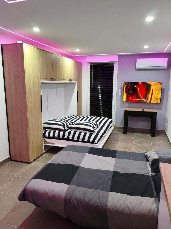 two beds in a room with purple lighting at l'Oracle Albinos in Nîmes