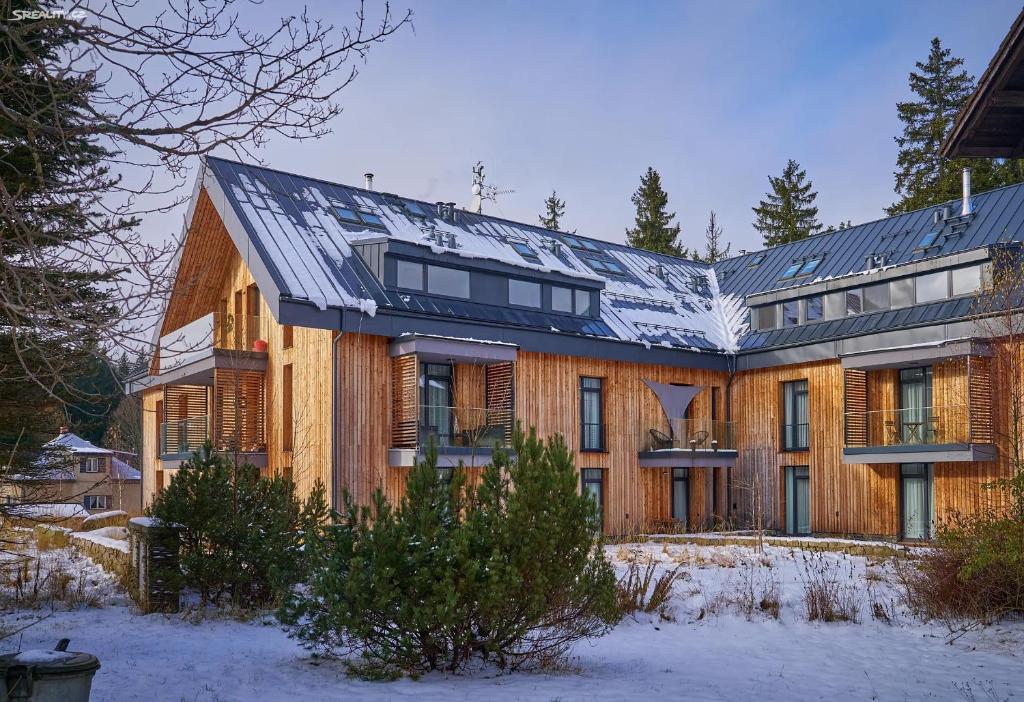 a large wooden house with a roof in the snow at Dolce Vita Harrachov in Harrachov
