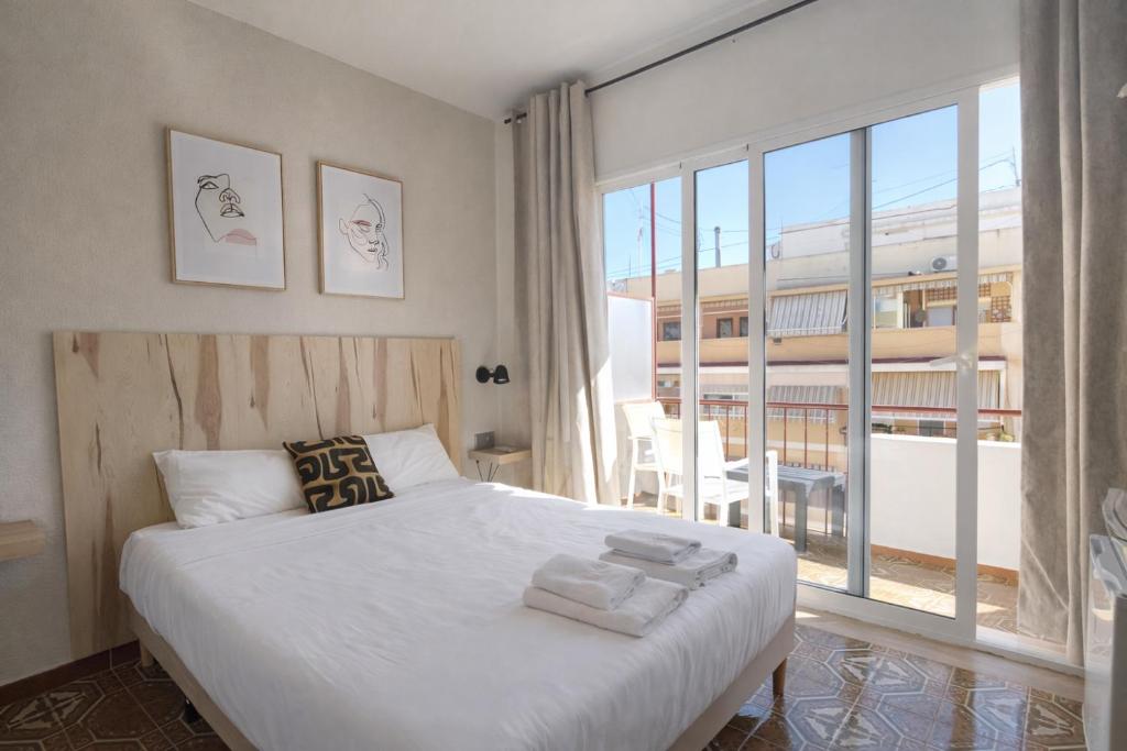 a bedroom with a white bed and a large window at CASA MILA SV19 guesthouse in Alicante