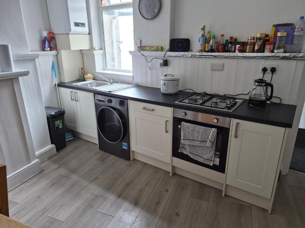 a kitchen with a stove and a washing machine at Double rooms in Crosby