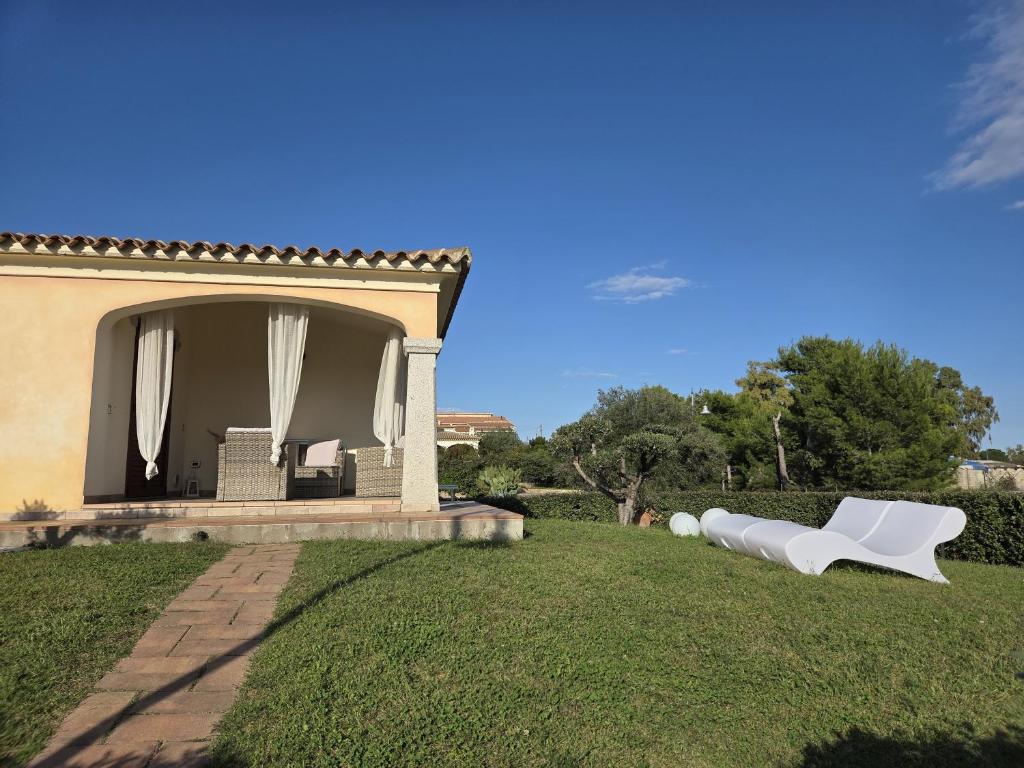 a yard with two white chairs and a house at Casa Nala - Villa con giardino in Budoni